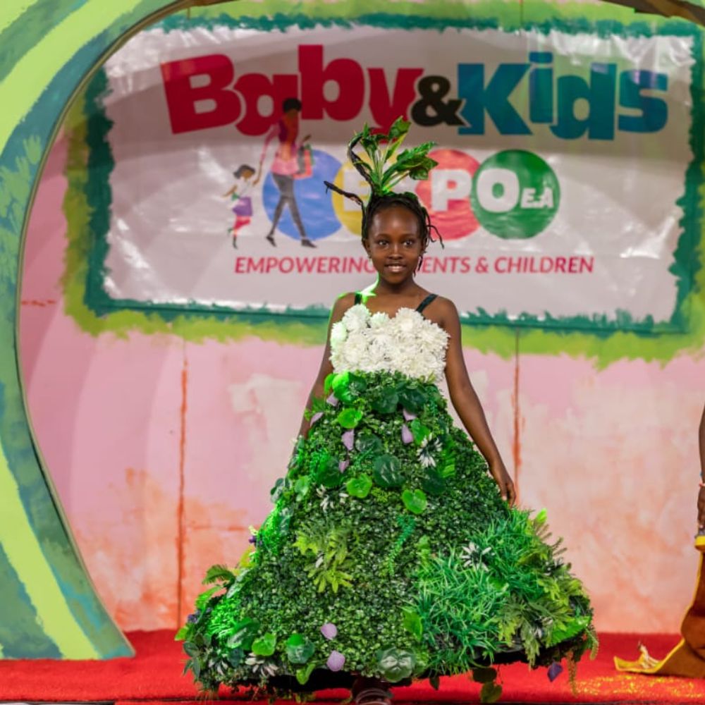 A young girl modeling a floral and botanical dress on stage at the Baby and Kids Expo fashion show.
